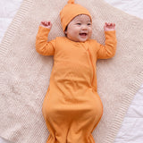 Laughing baby in the Amber bamboo sleep bag and matching hat on a knit blanket