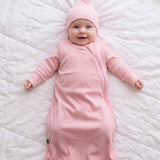 Baby in the Hugs & Giggles bamboo sleep bag in Blush with matching romper and knotted hat, top-down view