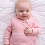 Close-up of the Blush ribbed bamboo sleep bag zipper and shoulder flap on a smiling baby
