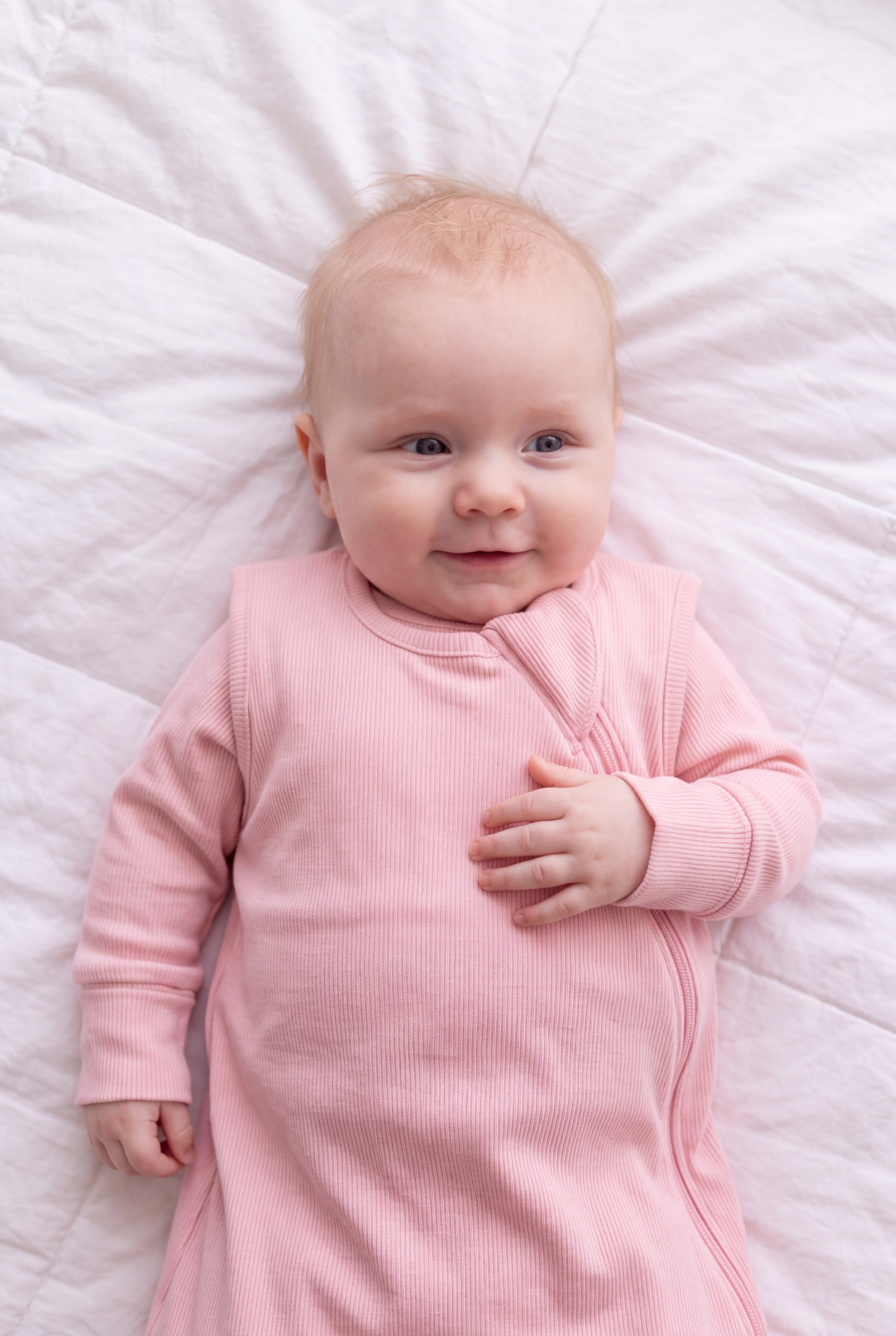Close-up of the Blush ribbed bamboo sleep bag zipper and shoulder flap on a smiling baby